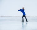 Caucasian woman in a blue sweater is skating on a frozen lake. The figure skater performs the program. Royalty Free Stock Photo