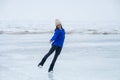 Caucasian woman in a blue sweater is skating on a frozen lake. The figure skater performs the program. Royalty Free Stock Photo