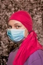 Caucasian woman with breast cancer wearing disposable face mask and pink chemo hat. Optimistic woman