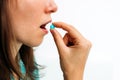 Caucasian woman brings a pill to her mouth in her hand