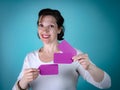 Caucasian Woman with brown hair holding purple cards on light blue background. Royalty Free Stock Photo