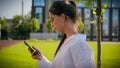 Caucasian woman businesswoman student business lady girl walk on street with green lawn using mobile phone check email Royalty Free Stock Photo