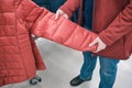 Caucasian woman chooses red warm jacket on a sintepon in store to buy. Close up