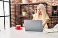 Caucasian woman doing video call with laptop scared and amazed with open mouth for surprise, disbelief face