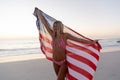 Caucasian woman holding and waving an US flag at the beach.