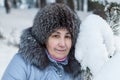 Caucasian woman face in fur hat near snowy pine branch