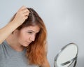 Caucasian woman finds gray hair and removes it with tweezers. Signs of aging.