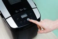 Caucasian woman finger presses the start button on bread maker Royalty Free Stock Photo