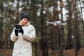 Caucasian woman flying aerial drone in autumn forest. Tech savvy middle age woman. Hobby modern