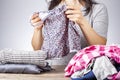 A caucasian woman is folding clean dresses on a wooden desk.