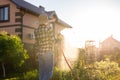 Caucasian woman gardener in work clothes watering the beds in her vegetable garden on sunny warm summer day. Concept of