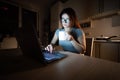 Caucasian woman in glasses sits at a wireless computer in the kitchen. A student prepares for the exam late at night and