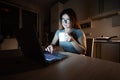 Caucasian woman in glasses sits at a wireless computer in the kitchen. A student prepares for the exam late at night and