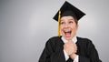 Caucasian woman in graduate gown dreamily holds her hands on her chest. Royalty Free Stock Photo