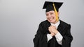 Caucasian woman in graduate gown dreamily holds her hands on her chest. Royalty Free Stock Photo