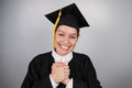 Caucasian woman in graduate gown dreamily holds her hands on her chest. Royalty Free Stock Photo