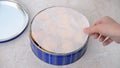 Caucasian woman hand removing parchment paper from full tin of danish butter cookies.