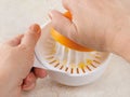 Caucasian woman hands squeeze juice from ripe sweet orange using plastic manual citrus juicer on a kitchen table. Vegetarian, raw