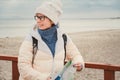 Caucasian woman in hat and jacket with backpack in winter sits on wooden pier on beach near North Sea. Denmark Copenhagen tourist Royalty Free Stock Photo
