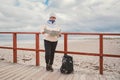 Caucasian woman in hat and jacket with backpack in winter sits on wooden pier on beach near North Sea. Denmark Copenhagen tourist Royalty Free Stock Photo