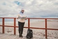 Caucasian woman in hat and jacket with backpack in winter sits on wooden pier on beach near North Sea. Denmark Copenhagen tourist Royalty Free Stock Photo