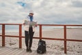 Caucasian woman in hat and jacket with backpack in winter sits on wooden pier on beach near North Sea. Denmark Copenhagen tourist Royalty Free Stock Photo