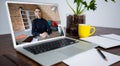 Caucasian woman havin gvideo call on screen of laptop on desk