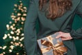 Caucasian woman hiding gift box with golden ribbon behind her back Royalty Free Stock Photo