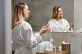 caucasian woman hold bottle with moisturizing drops use beauty product for healthy hand skin in bathroom