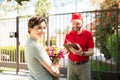 Caucasian woman holding flowers next to a delivery worker Royalty Free Stock Photo