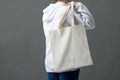 Caucasian woman holding over the shoulder white canvas bag with copy space on grey background Royalty Free Stock Photo