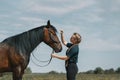 Caucasian woman holding reins of horse with hand in outdoors