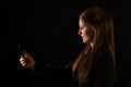 Caucasian woman holding smartphone in front of her face with black background Royalty Free Stock Photo