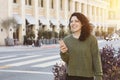 Young Female Calls a Ride Share on her Smart Phone - Smiling in the City with Warm Lighting