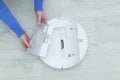 Caucasian woman inserts container with water into a robot vacuum cleaner