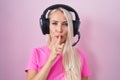 Caucasian woman listening to music using headphones asking to be quiet with finger on lips Royalty Free Stock Photo