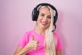 Caucasian woman listening to music using headphones doing happy thumbs up gesture with hand Royalty Free Stock Photo