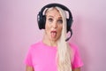 Caucasian woman listening to music using headphones sticking tongue out happy with funny expression Royalty Free Stock Photo