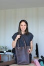 Caucasian woman making brown leather handmade bag at atelier.