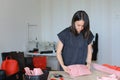 Caucasian woman making pink leather wallet at home atelier.