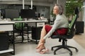 Caucasian woman massaging her tired legs while sitting in the office. Royalty Free Stock Photo