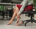 Caucasian woman massaging her tired legs while sitting in the office. Cropped. Royalty Free Stock Photo