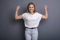 Caucasian woman in neutral casual outfit standing on a neutral grey background. Portrait with emotions: angry, pain, sickness and