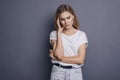 Caucasian woman in neutral casual outfit standing on a neutral grey background. Portrait with emotions: angry, pain, sickness and