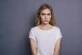 Caucasian woman in neutral casual outfit standing on a neutral grey background. Portrait with emotions: angry, pain, sickness and