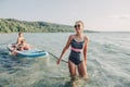 Caucasian woman parent riding kids children boys on paddle sup surfboard in water. Royalty Free Stock Photo