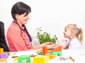 A caucasian woman, a pediatrician, a psychotherapist, is making contact with a girl patient, a child of 3-4 years old