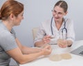 Caucasian woman and plastic surgeon touching and choosing breast implants. Royalty Free Stock Photo