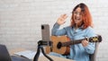 Caucasian woman playing guitar live on a smartphone. The girl leads a music video blog