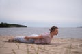 Caucasian woman practicing yoga, doing Salabhasana pose variation on beach